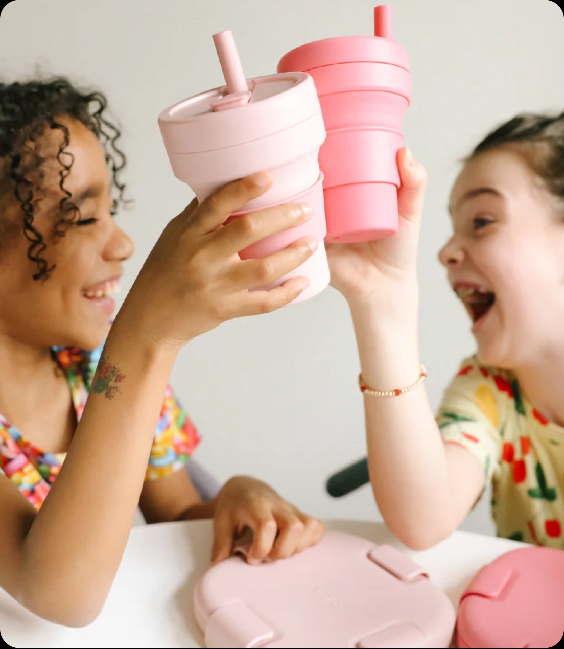 Two children cheer with their Stojo cups