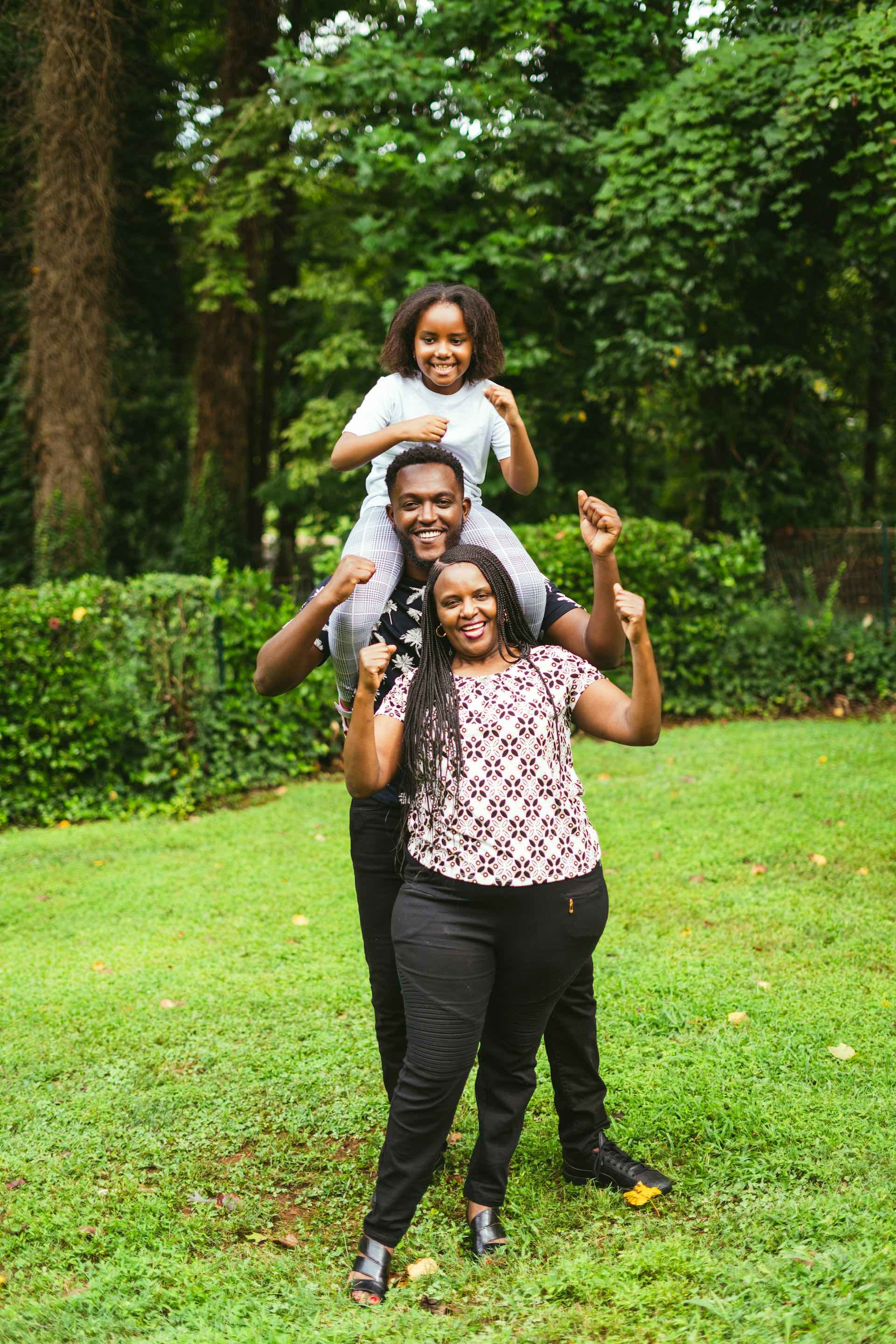 Family of 3 holding their arms in the air